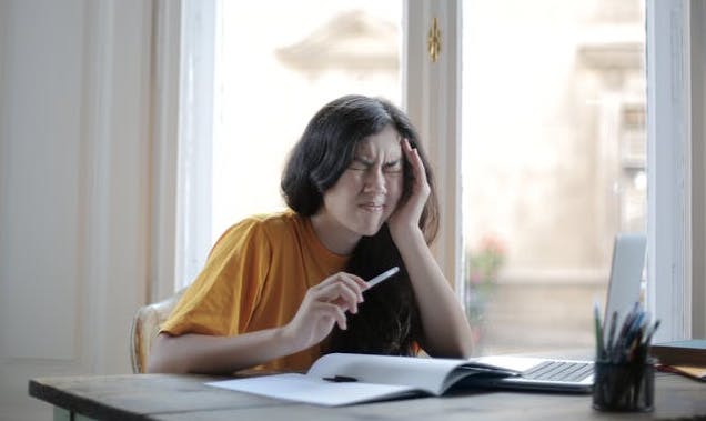 Ragazza con mal di testa miotensivo mentre sta studiando