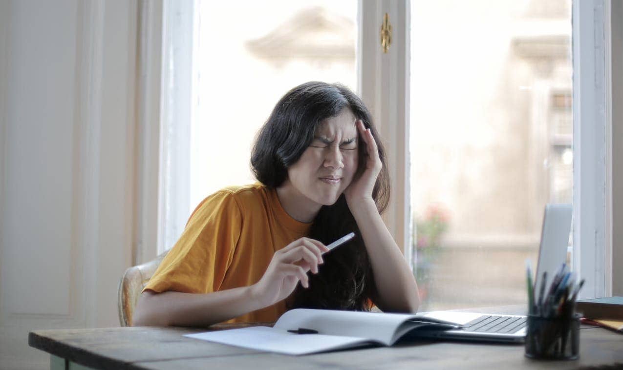 Ragazza con mal di testa miotensivo mentre sta studiando